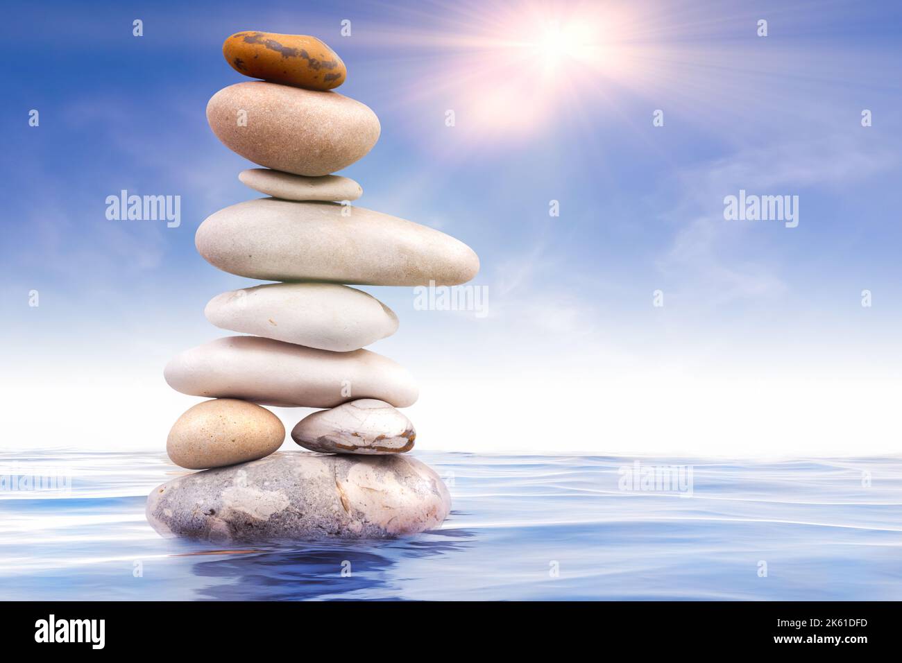 Blue Zen Rocks Zen stones balanced in water with blue sky and morning sunlight rays ...