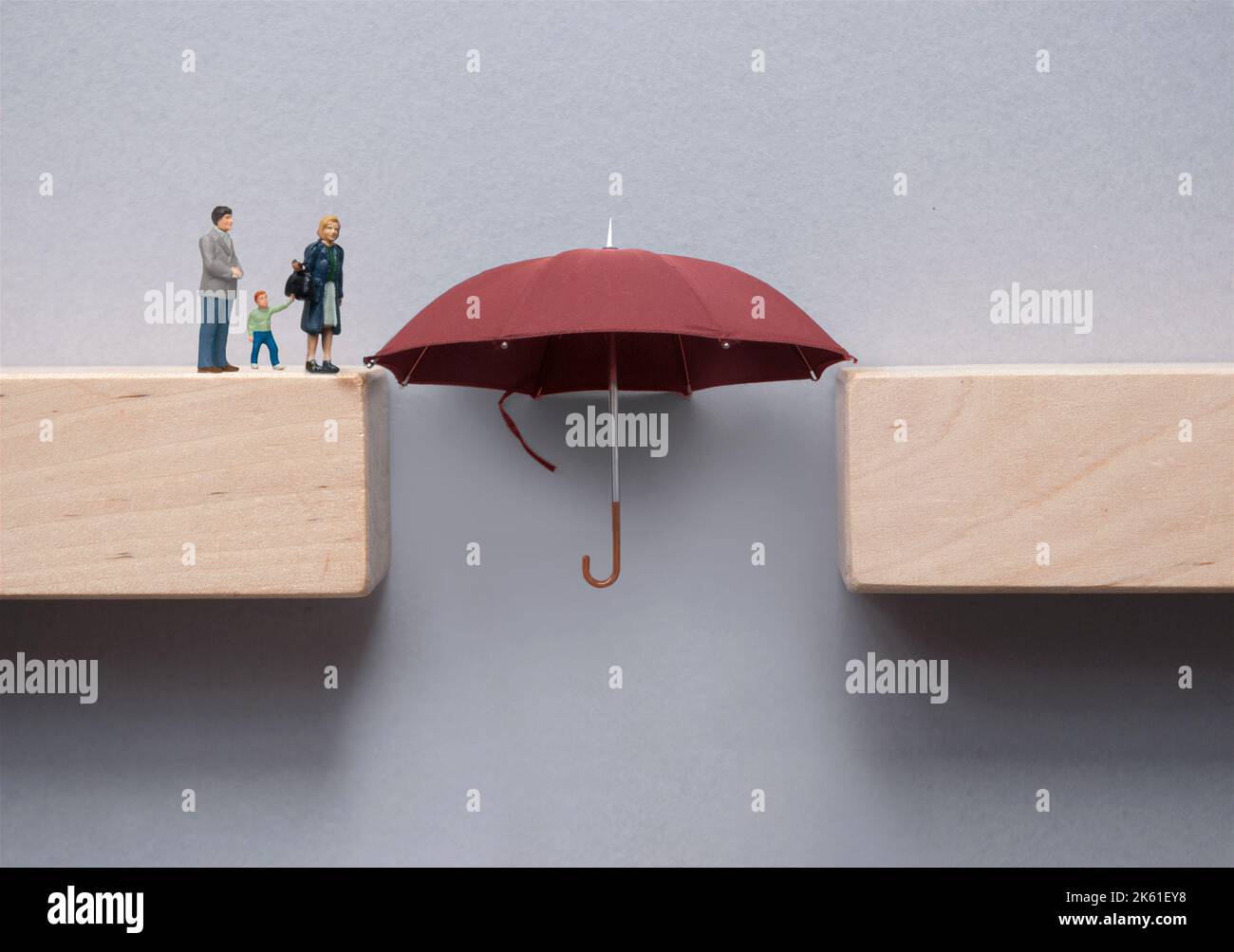 Family insurance concept; umbrella bridging the gap between wooden blocks and safe crossing for family Stock Photo