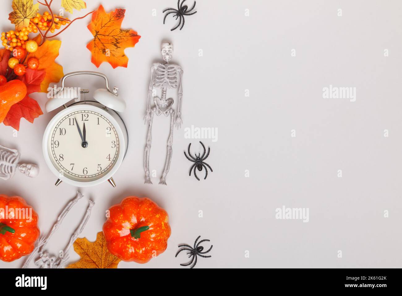 Alarm clock with fallen leaves pumpkins skeletons spiders. Transitional change of autumn time, change of seasons halloween Stock Photo