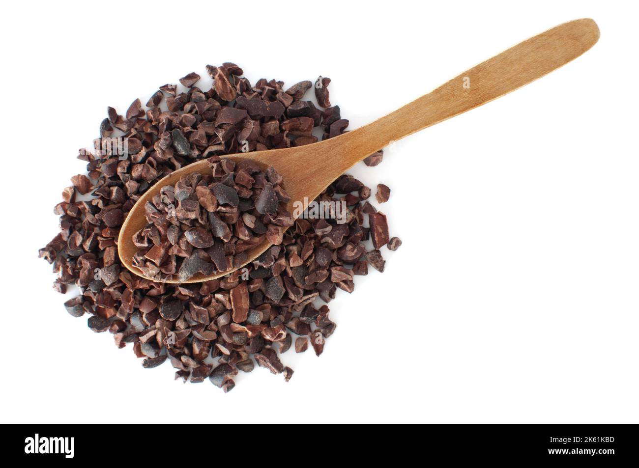 Top view of organic raw cacao nibs pile with natural wood spoon on. Isolated on white background with selective focus. Stock Photo