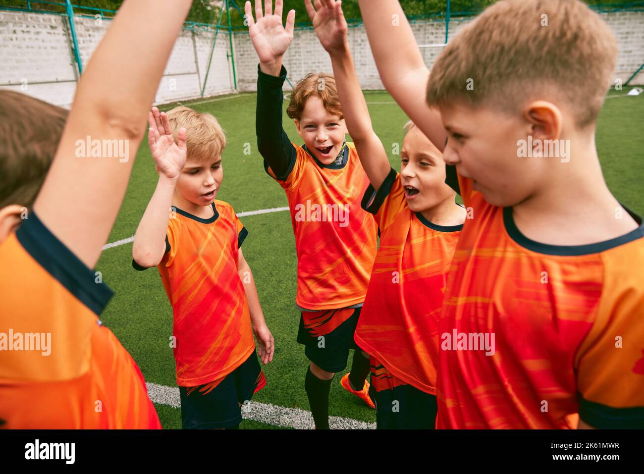 Soccer junior team with medals and trophy. Sportive boys celebrating victory. Concept of win, sport, studying, achievements, success. Stock Photo