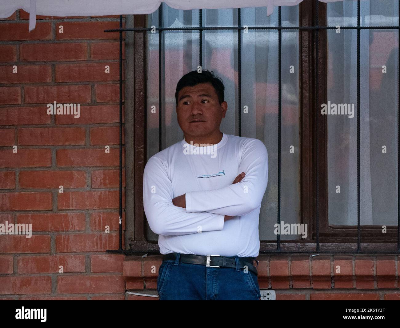 La Paz, Bolivia - September 10 2022: Bolivian Man Leaning against Window Watching Children's Birthday Party Stock Photo