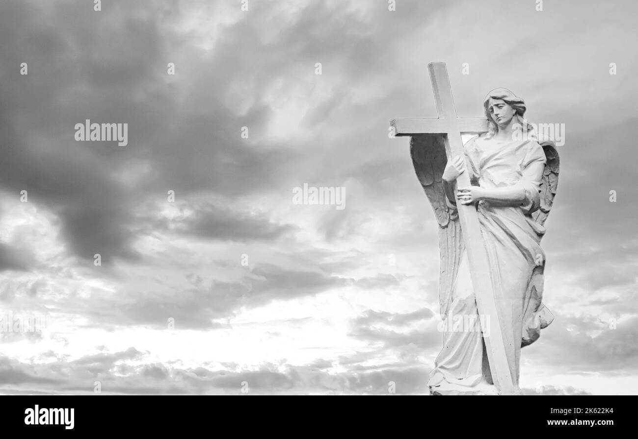 Black and white holy angel with wings holding large cross on sky background Stock Photo