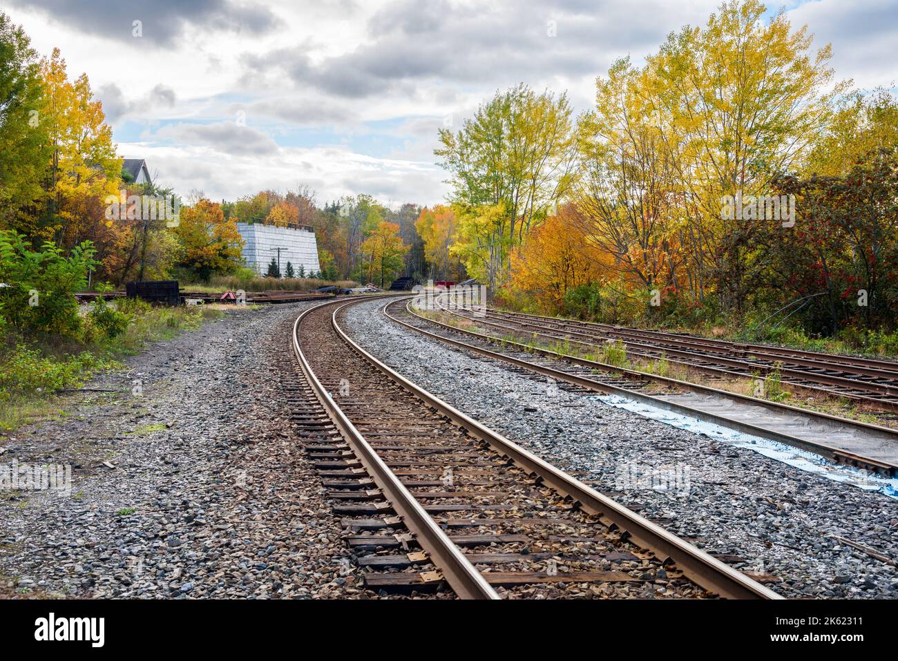 Multiple railroad tracks with switches on a cloudy autumn day. Colourful autunalm trees line the tracks. Stock Photo