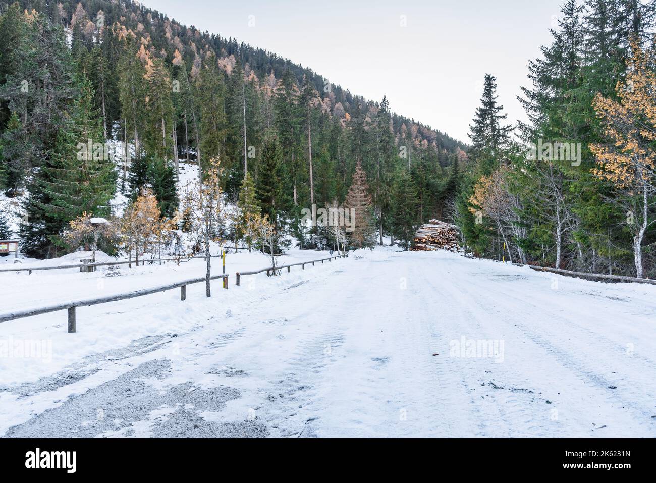 Empty snowy parking lot at the foot of forested slopes in the mountains in autumn Stock Photo