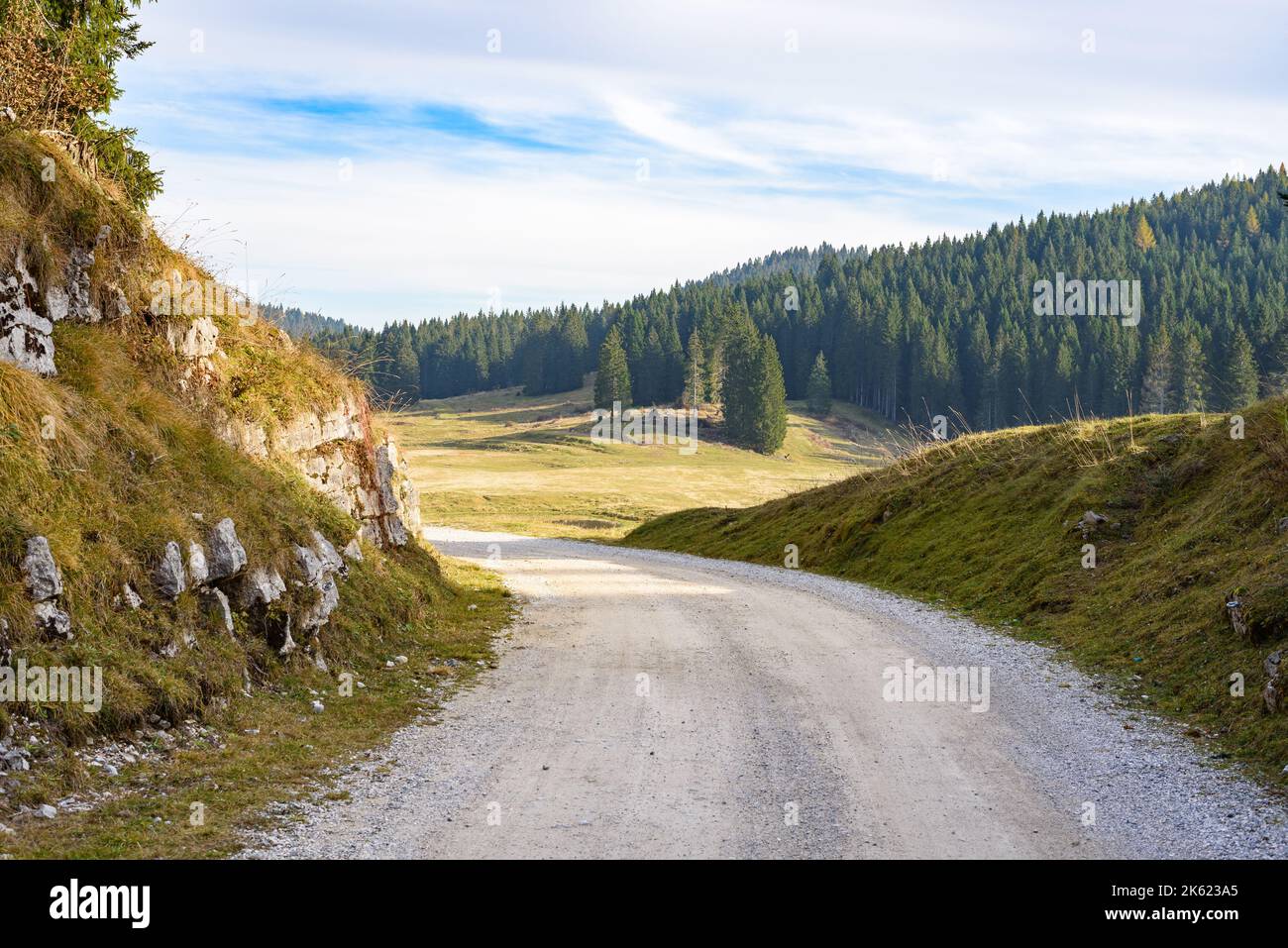 Winding gravel road in the mountains at sunset in autumn Stock Photo