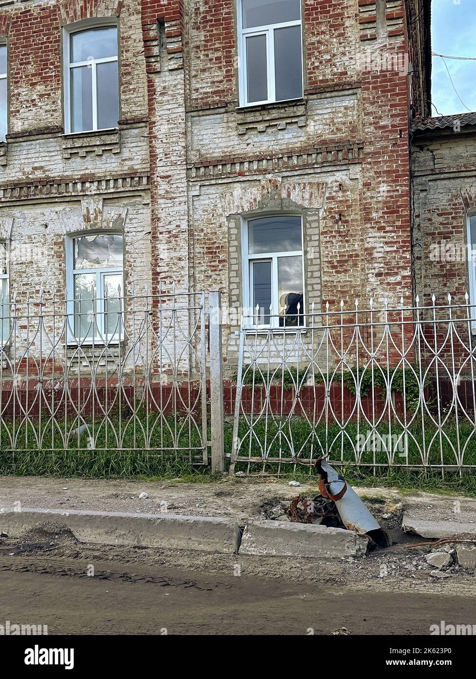 Russian MLRS Grad projectile on the street next to house on liberated from occupation Kupiansk town in Ukraine. Result of Russian bombardment. Concept Stock Photo