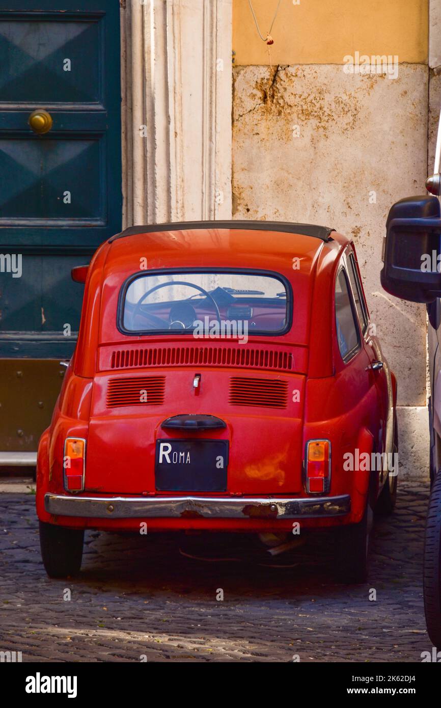 A vertical shot of a beautiful red Fiat 500 car on the streets of Rome ...