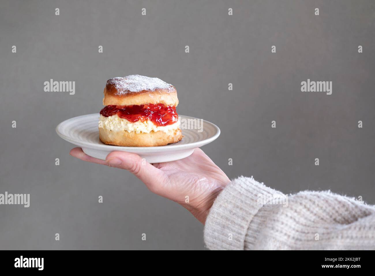 A fresh traditional English home made scone. The cake is split and filled with jam and topped with thick clotted cream. A delicious Devon cream tea. Stock Photo