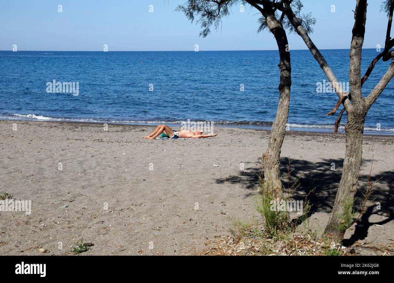 Man sunbathing, relaxing on a beach,  Lesvos (Lesbos/Mitylene) . Stock Photo