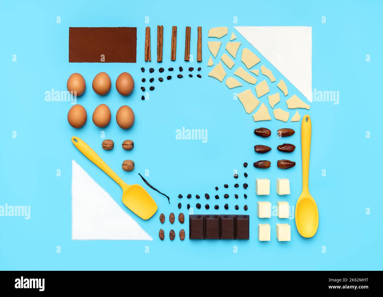 Top view with ingredients and utensils for baking arranged symmetrically on a blue table. Food knolling with ingredients for baking dessert. Stock Photo