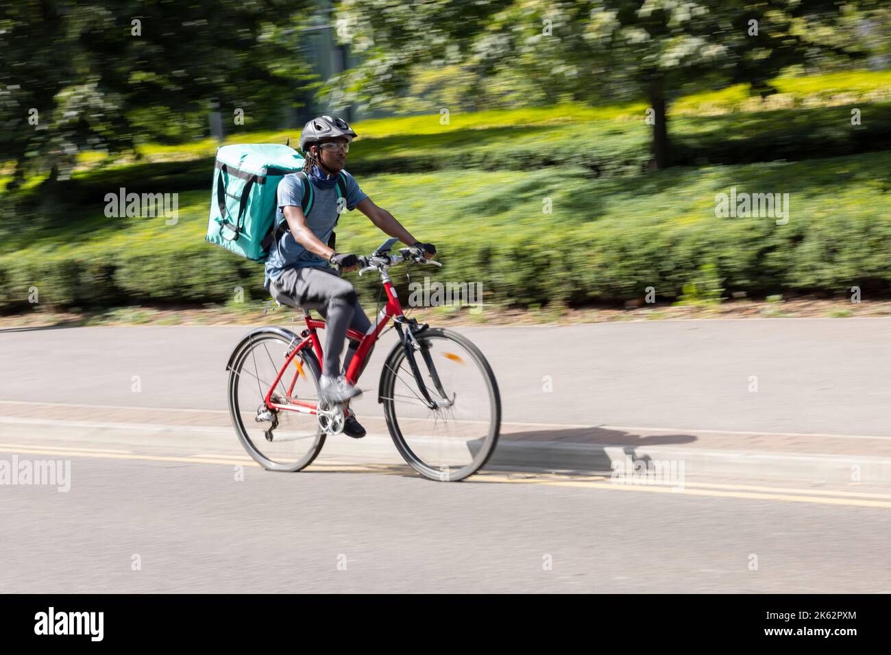 Courier On Bike Delivering Takeaway Food In City Stock Photo