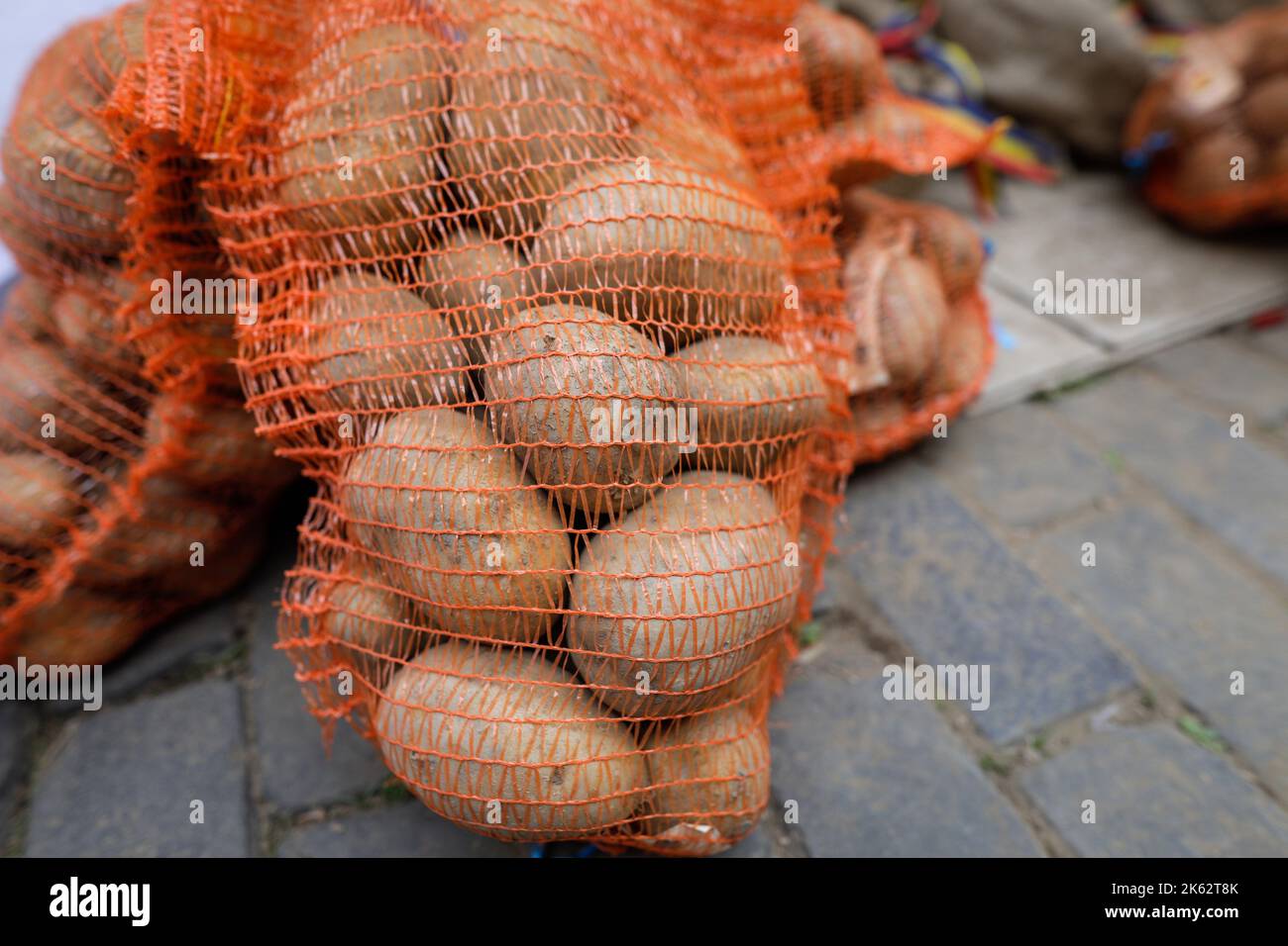 Shallow depth of field (selective focus) details with potatoes in a net sack in an european farmers market. Stock Photo