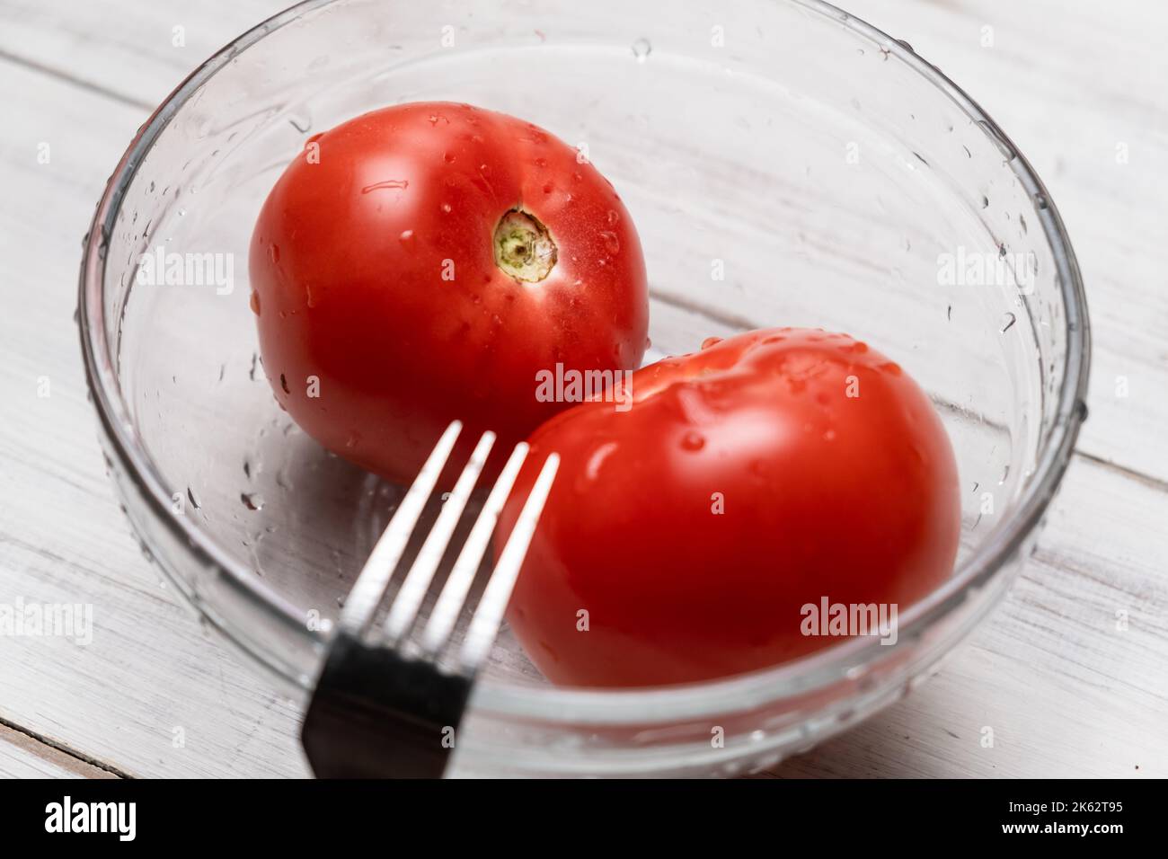 Peeling tomatoes in boiling water. Piercing tomatoes with a fork before