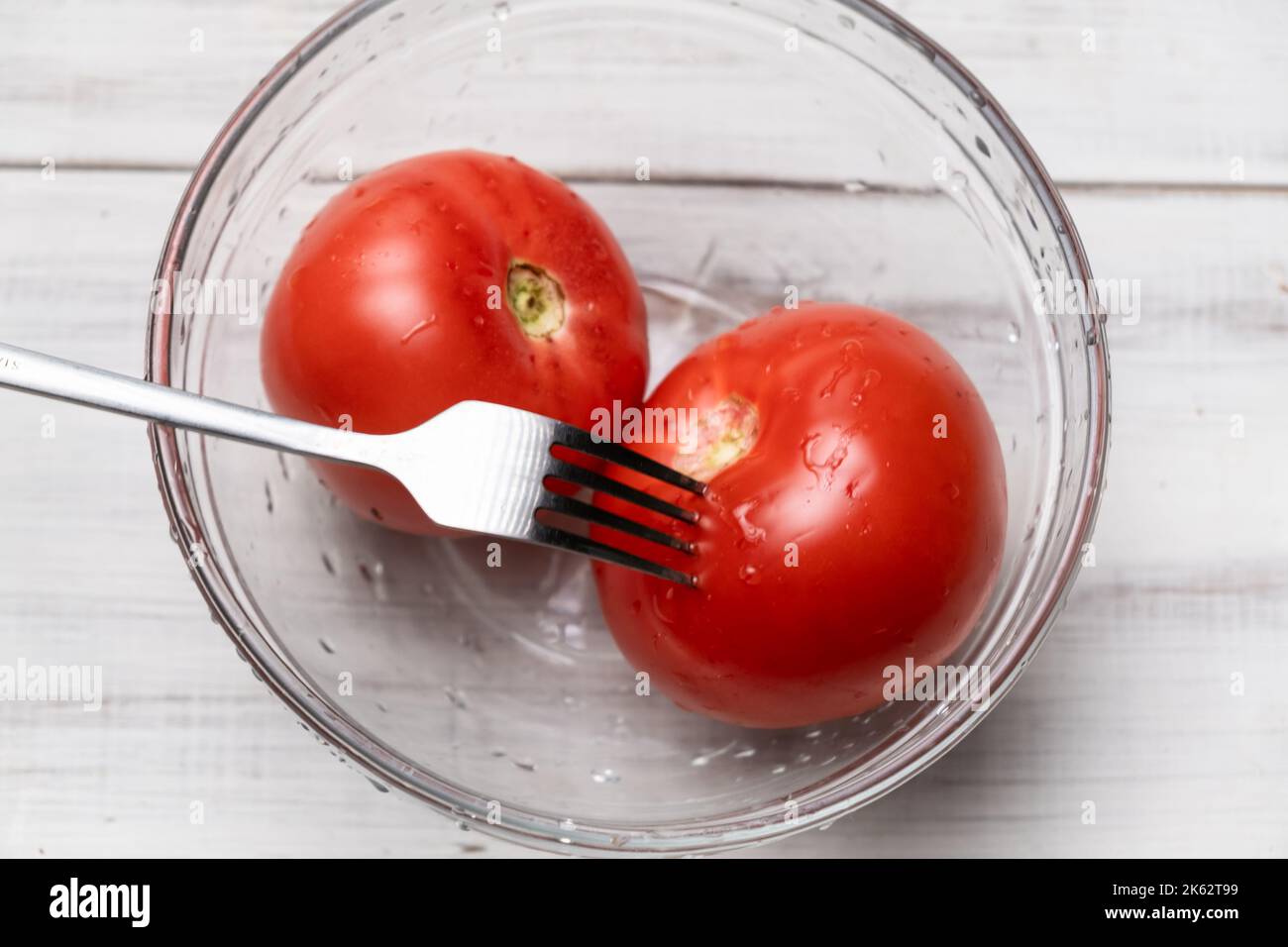 Peeling tomatoes in boiling water. Piercing tomatoes with a fork before
