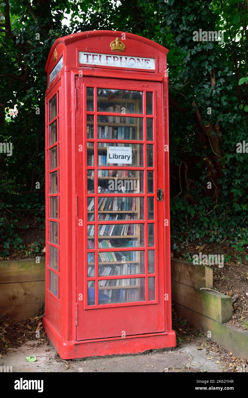 Old traditional UK red pubic telephone box repurposed as free lending library filled with books Stock Photo