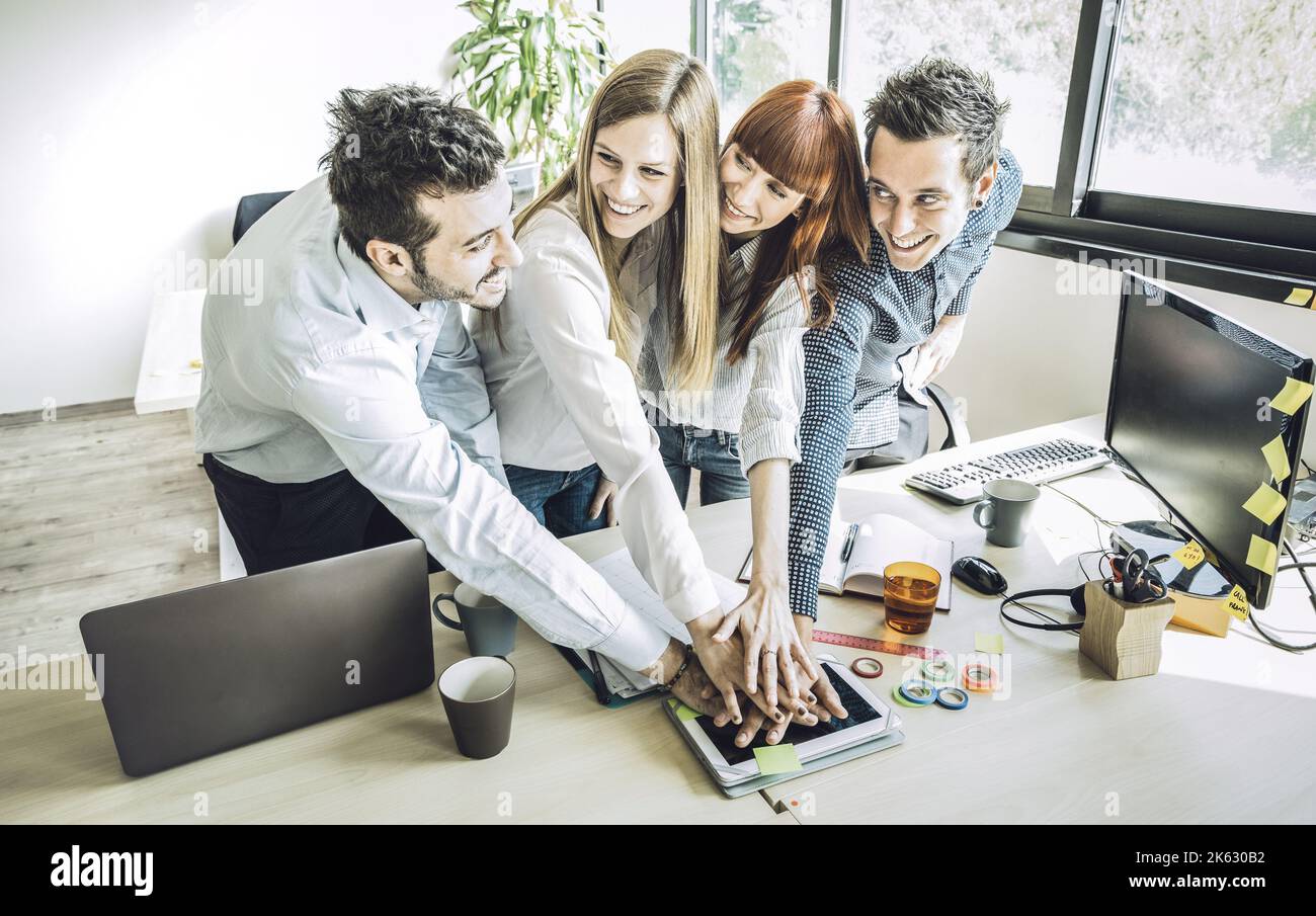 Group of young people employee coworkers stacking hands in urban coworking place studio - Human resources business concept at working time - Start up Stock Photo