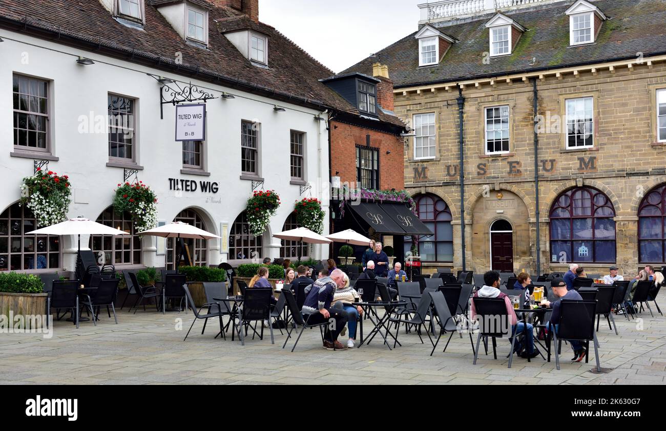 People siting outside eating, drinking in front of the Tilted Wig bed & breakfast hotel and public house in Warwick town square Stock Photo