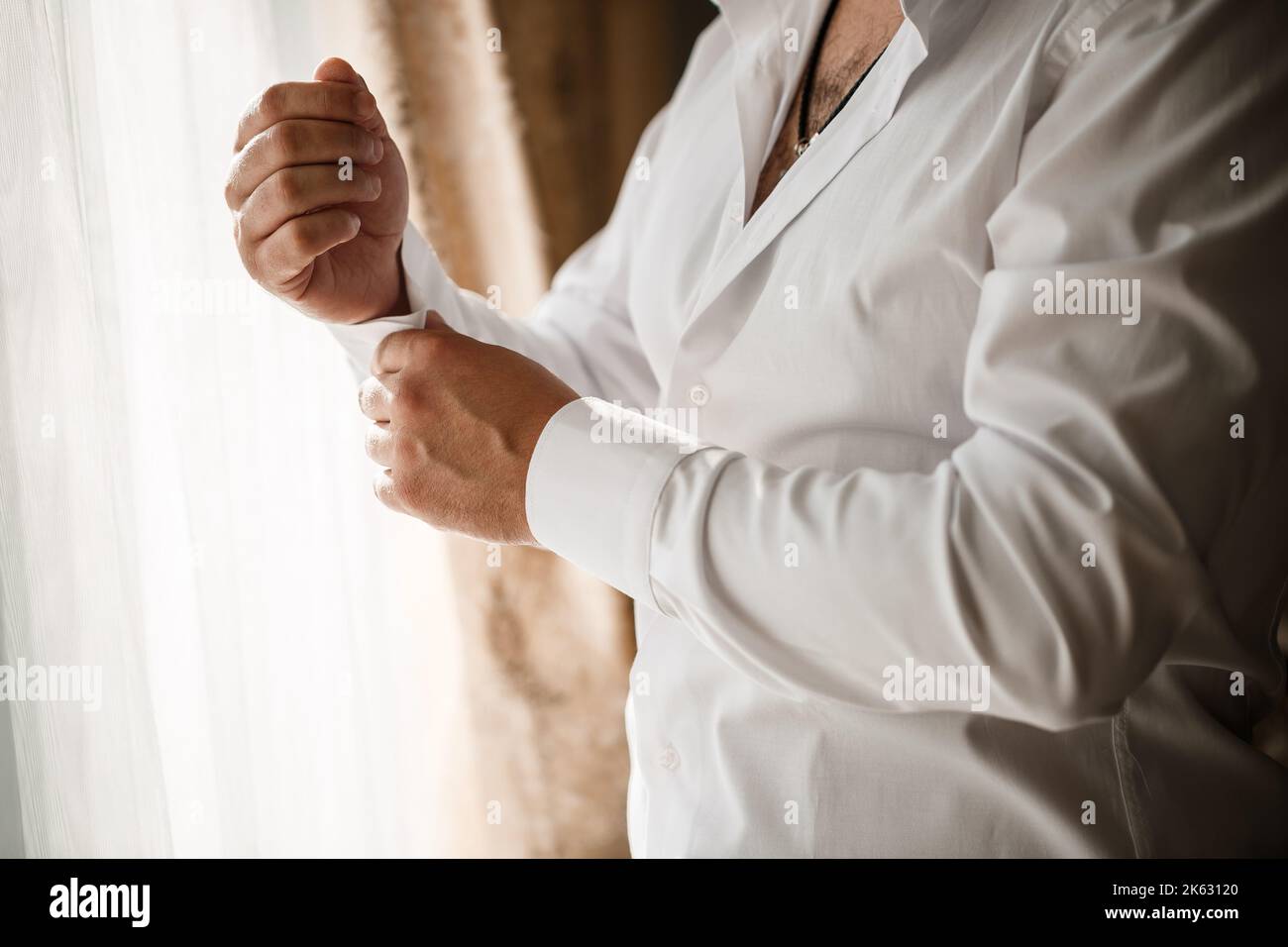 Man businessman buttoning a button on the sleeve of a white dress shirt ...