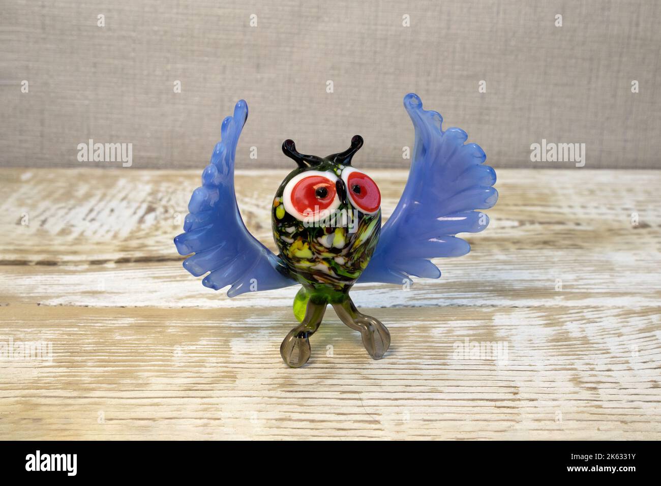 Bright glass owl figurine on rough wooden background front view Stock Photo