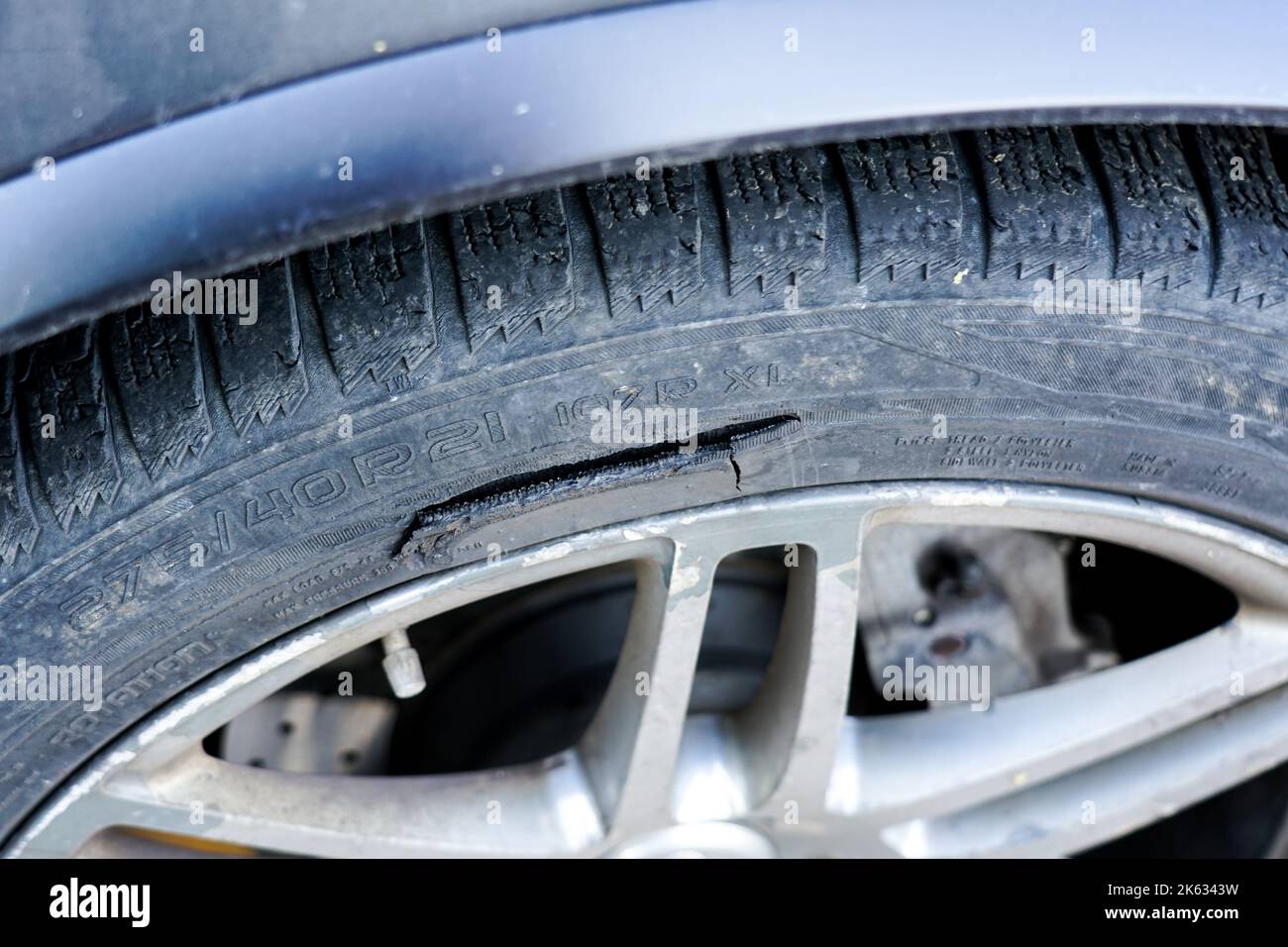 A large long mechanical cut on the sidewall of a passenger car tire