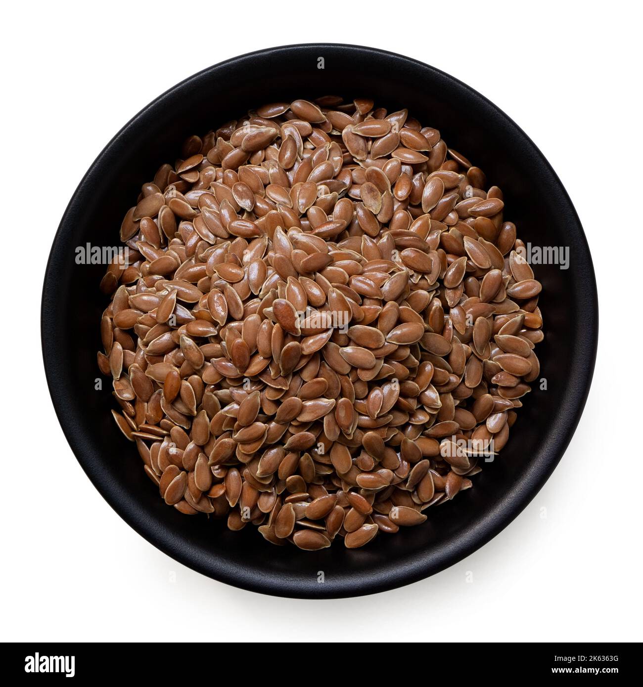 Flax seeds in a black ceramic bowl isolated on white. Top view. Stock Photo