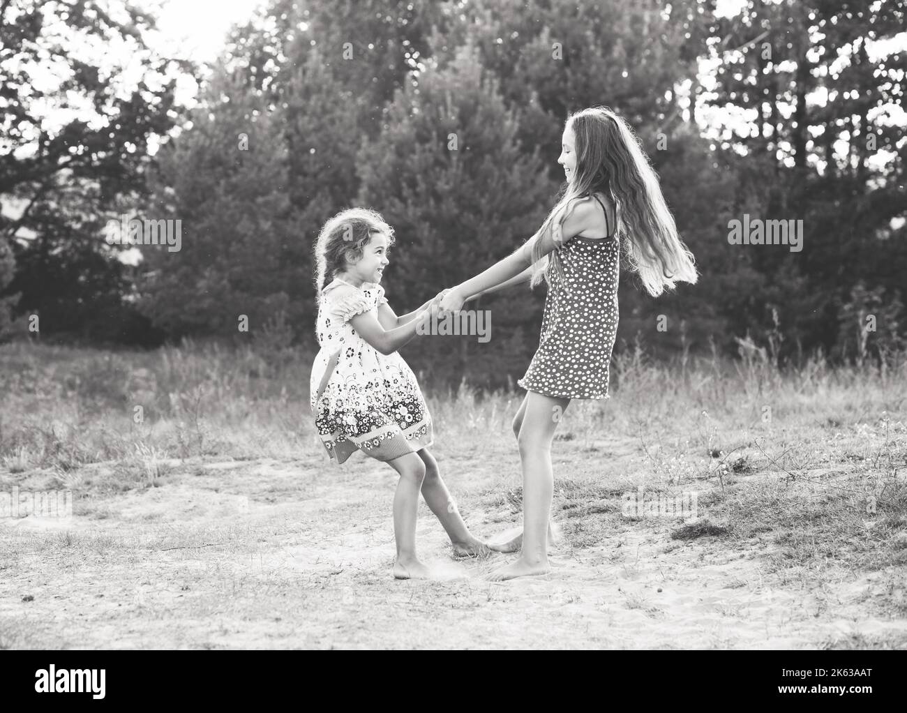 Black and white portrait of Two Happy cute  little girls embracing and dancing at sunny summer day outdoors Stock Photo