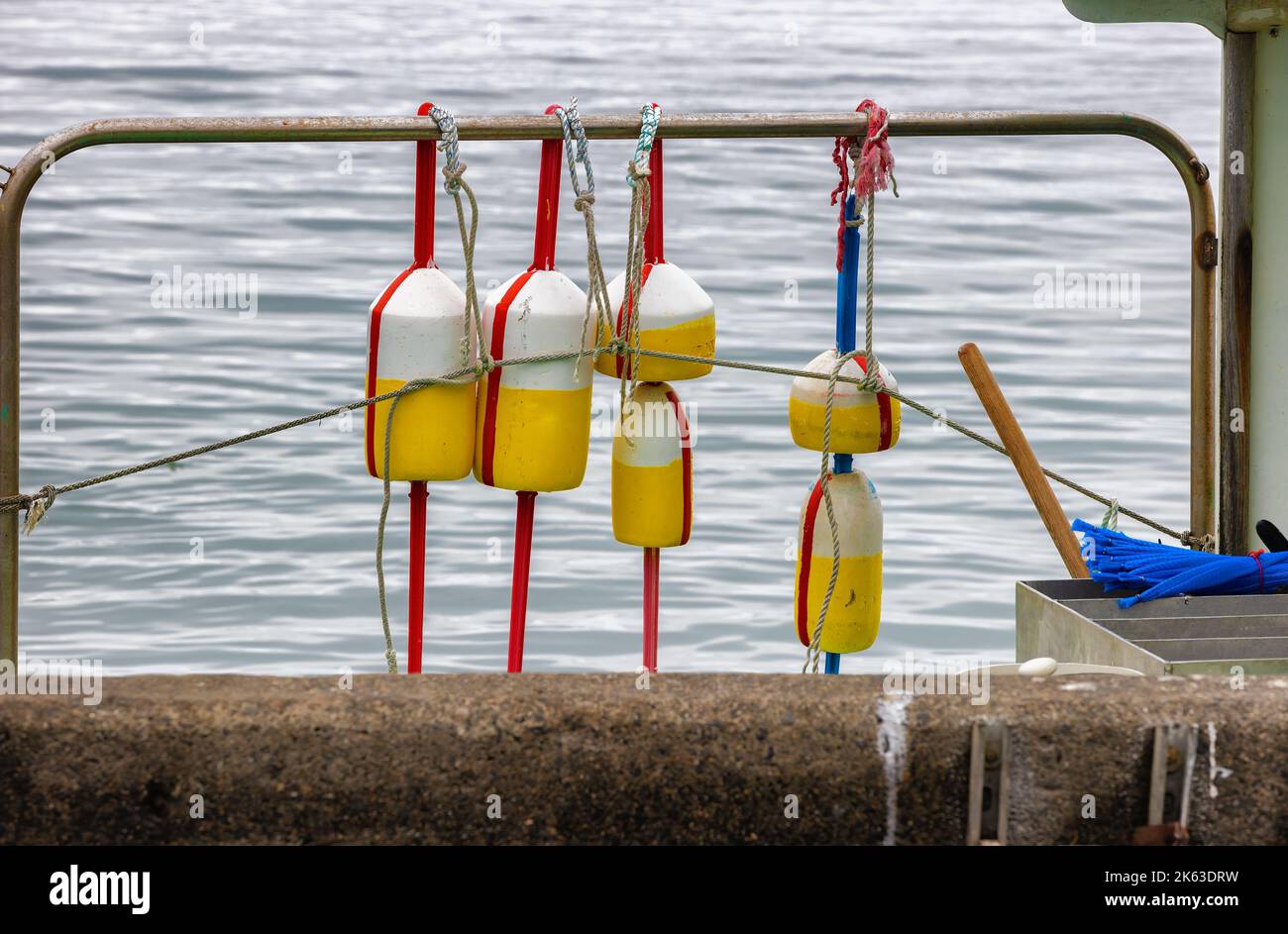 Close up of yellow and white floats hanging from a metal bar at Plymouth Harbor. Stock Photo
