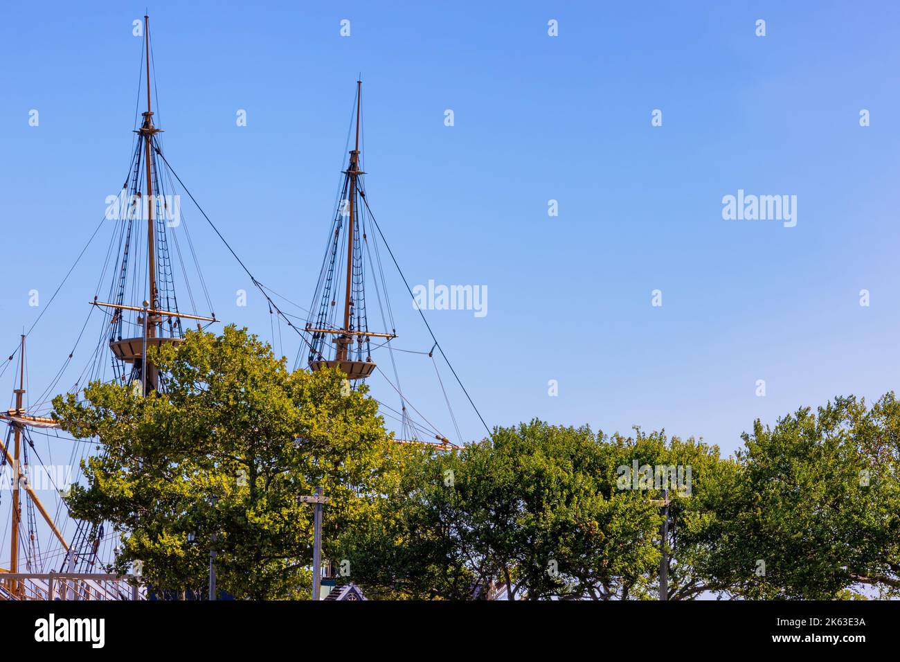 Tall Ship mast of the Mayflower II behind tree tops seen from the waterfront at Plymouth Massachusetts. Stock Photo