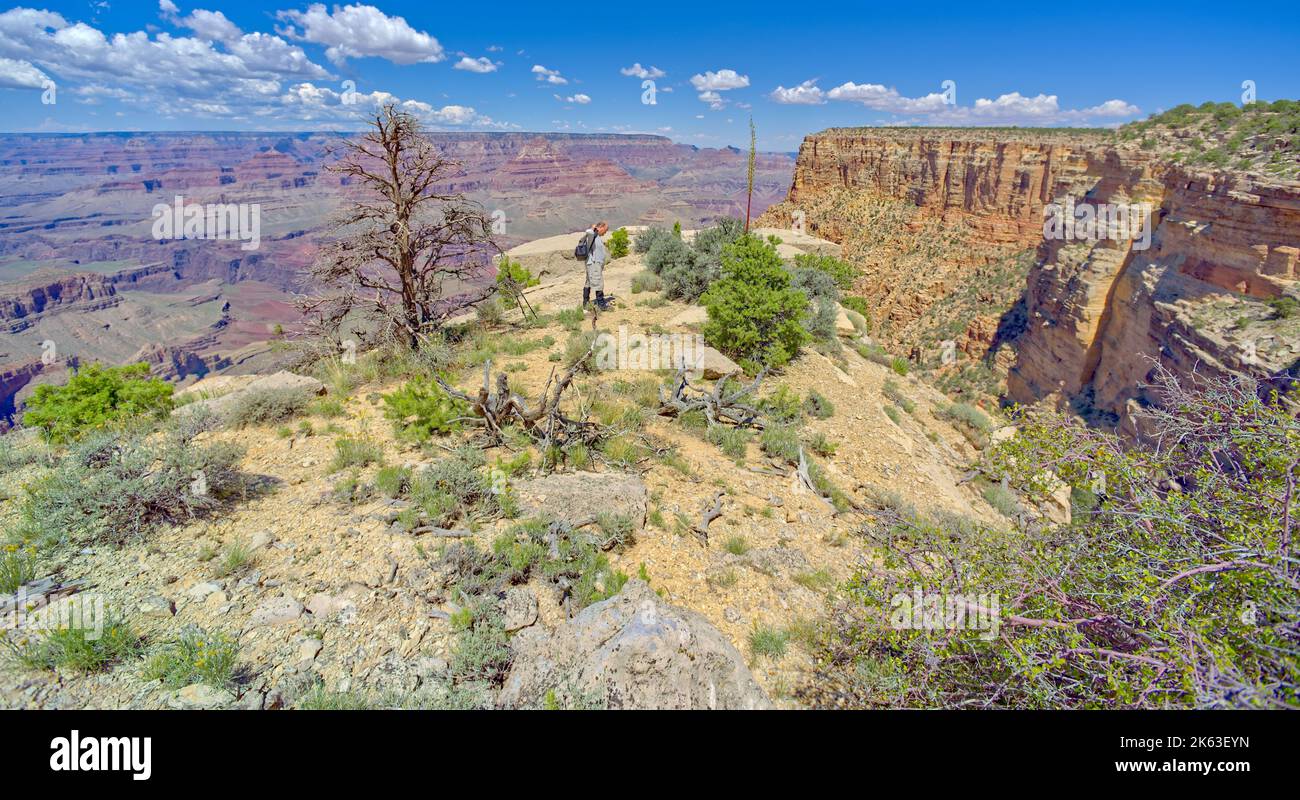A hiker putting on a backpack before heading away from a cliff at Grand ...
