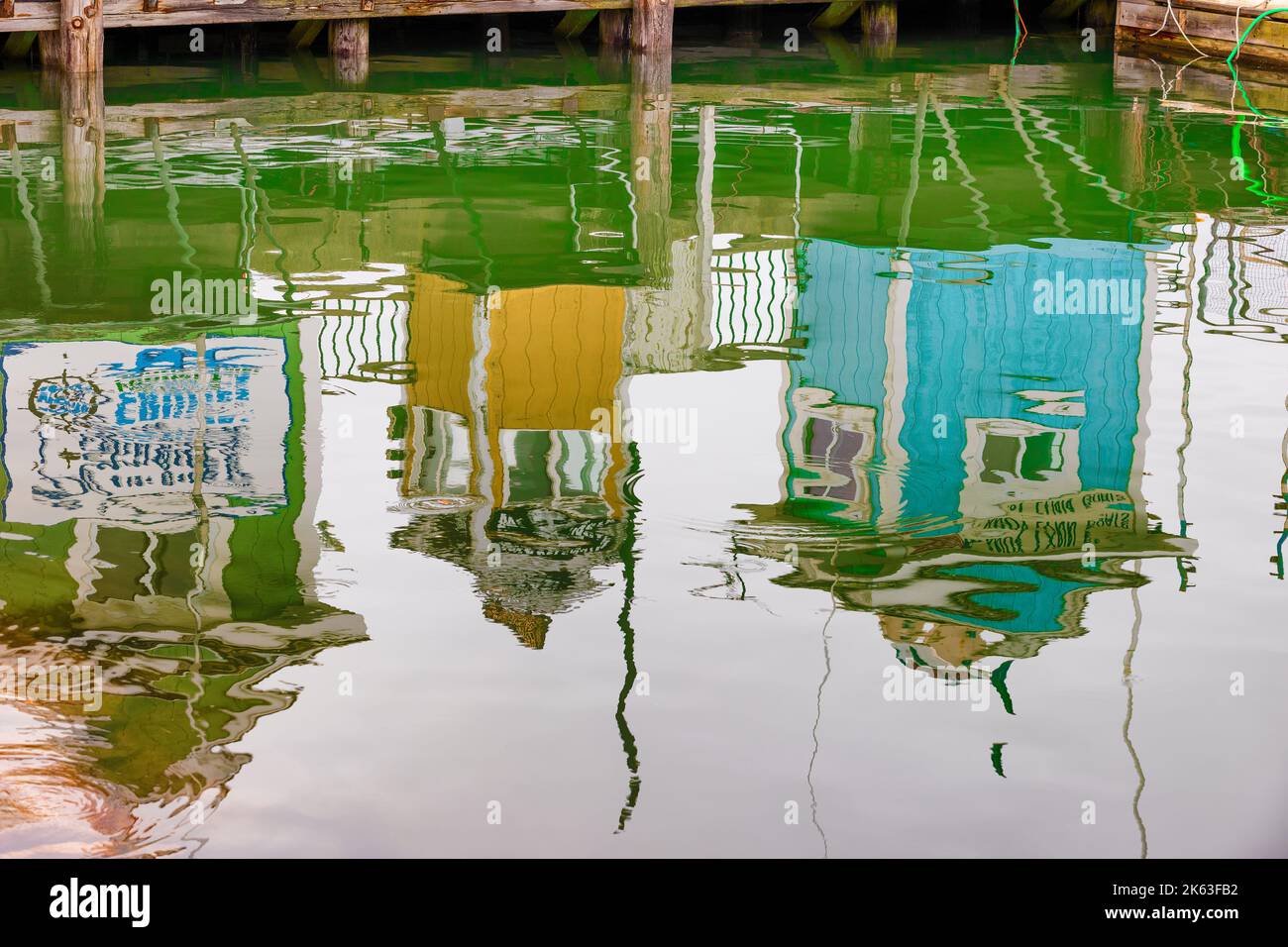 Plymouth, Massachusetts, USA - September 12, 2022: Reflections in seawater of tiny buildings on a dock at Plymouth Harbor. Stock Photo