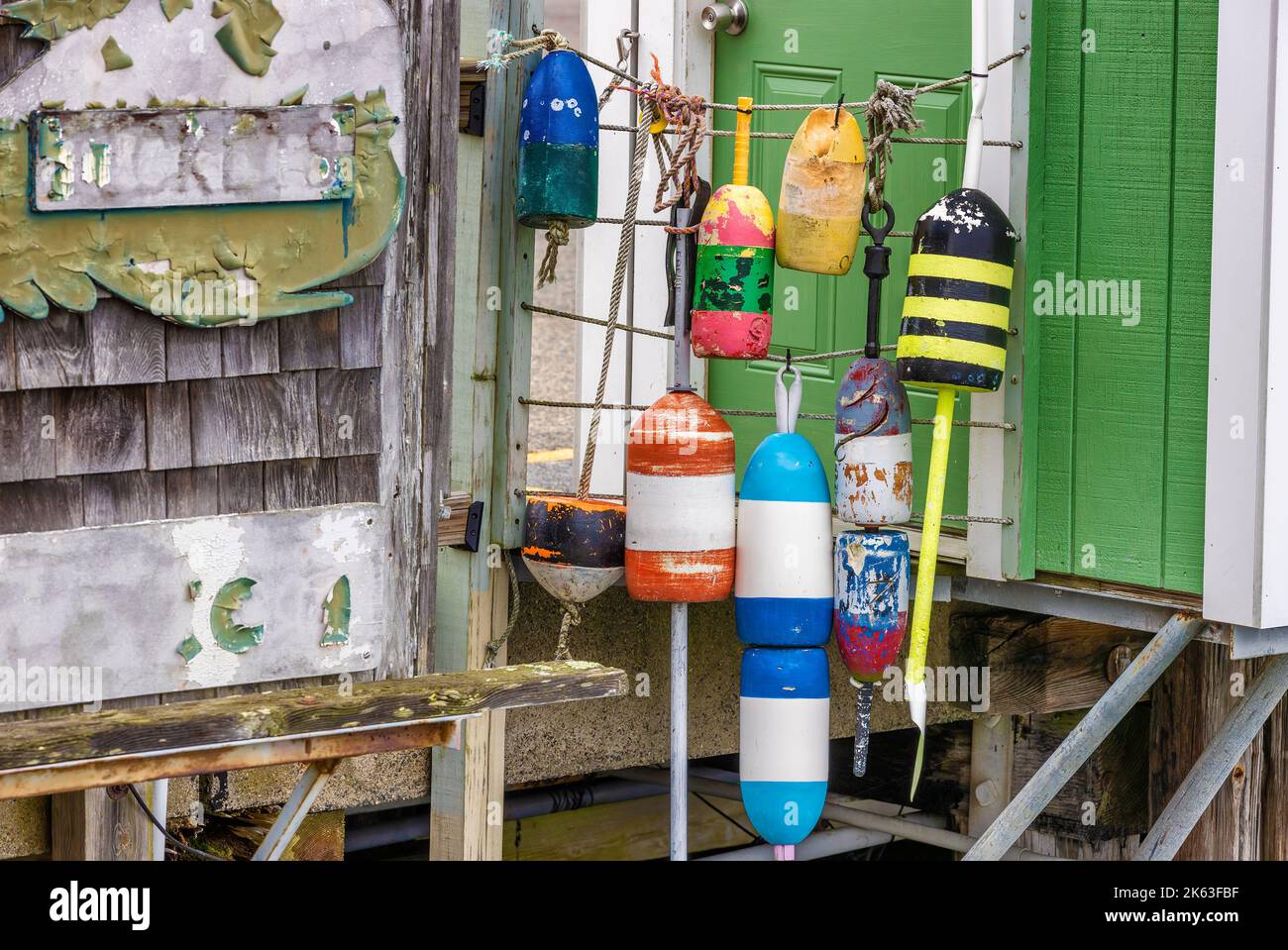 Close up of floats hanging from ropes between two tiny buildings on a dock at Plymouth Harbor. Stock Photo