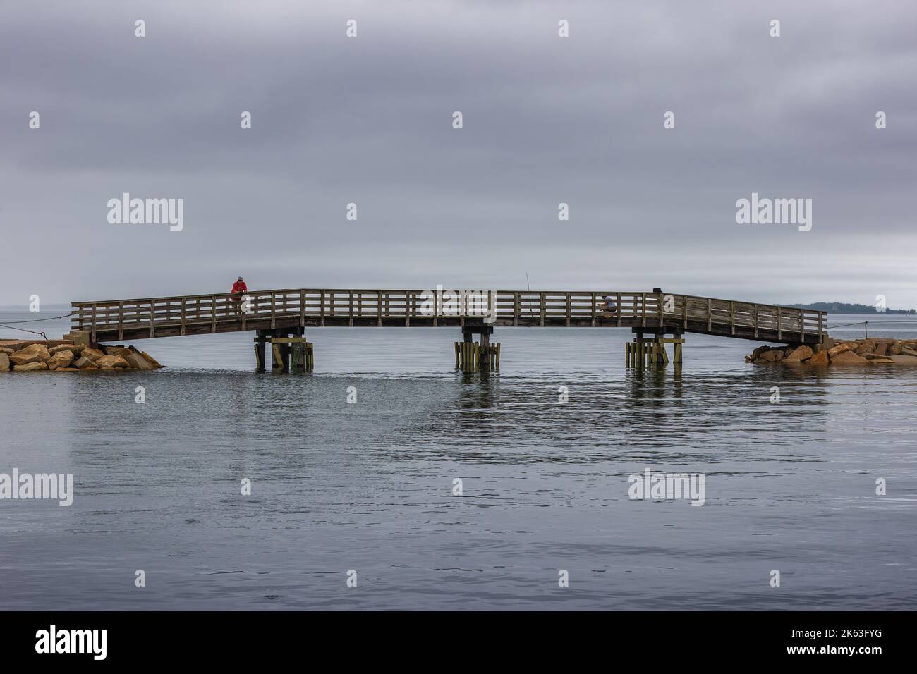 Plymouth, Massachusetts, USA - September 12, 2022: Tow men fishing from bridge along the dike in Plymouth Harbor. Stock Photo