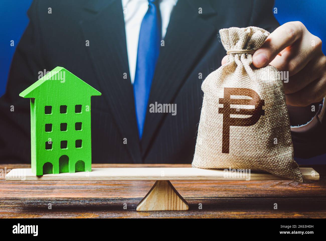 Businessman puts philippine peso money bag on scales and green house