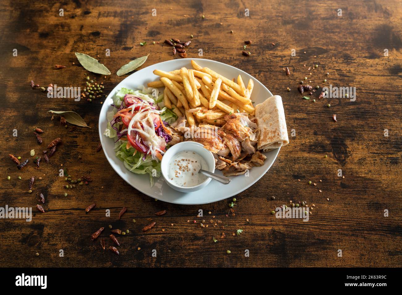 Kebab plate with french frizes and white sauce on a wooden table Stock Photo