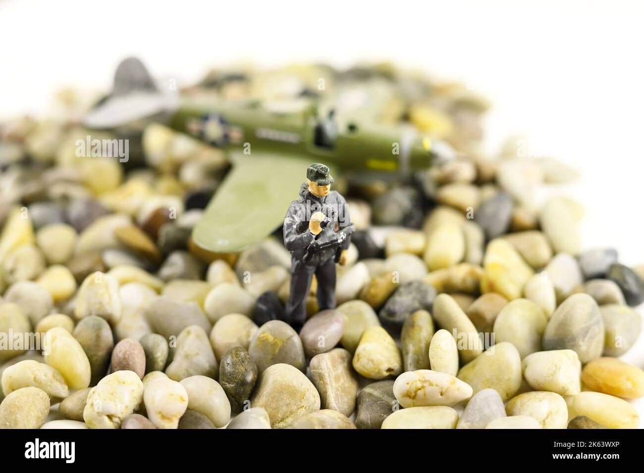 Toy figure of soldier on stones on blurred airplane background. Military war concept. Stock Photo