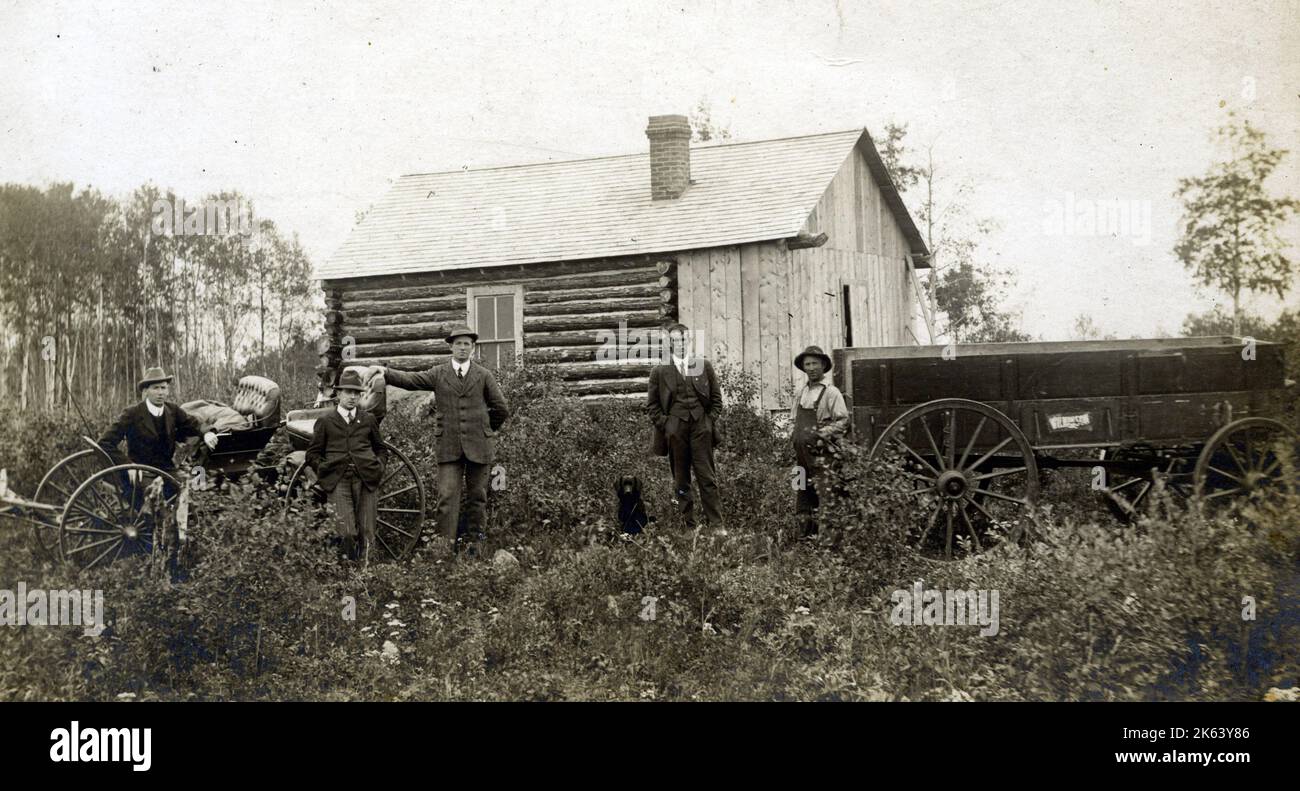 Group of men, log cabin, horses buggy and farm vehicle possibly near