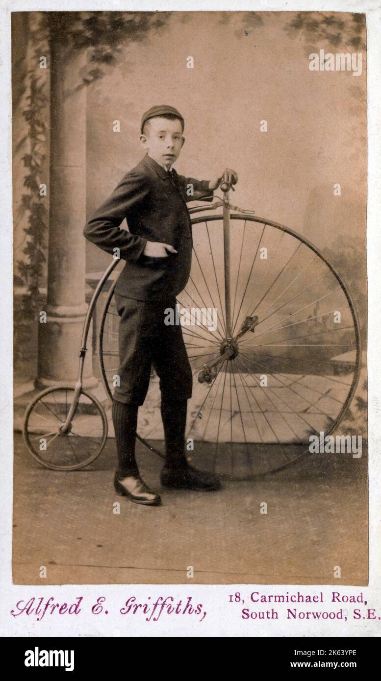 A delightful Victorian carte-de-visite photograph of a young boy standing proudly alongside his Penny Farthing bicycle Stock Photo