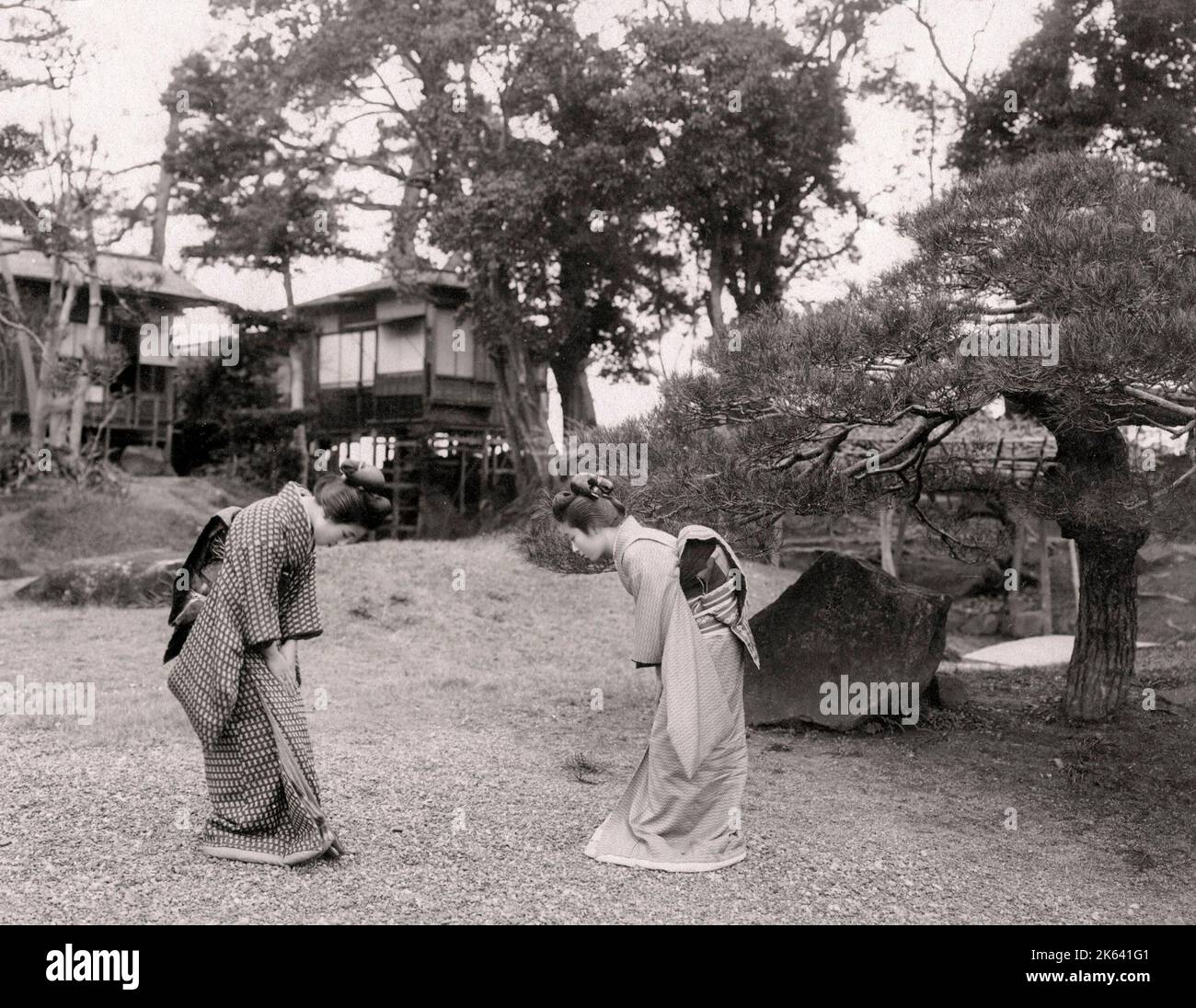 Vintage 19th century photograph: Two young Japanese women bowing to each other in greeting. Stock Photo
