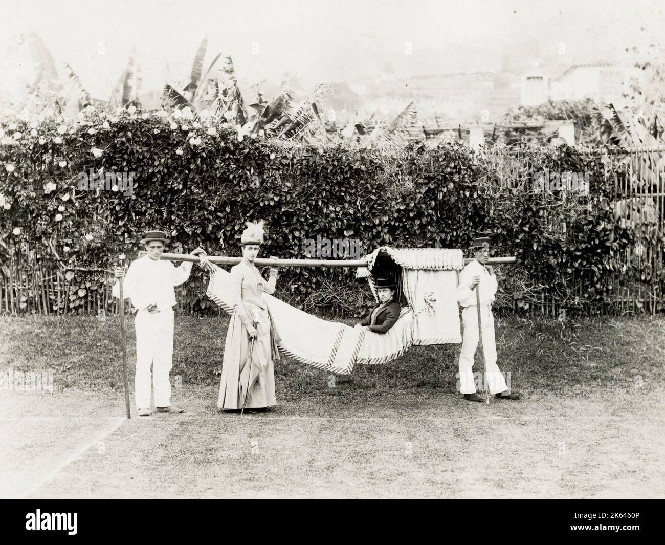 Vintage 19th century photograph - woman being carrried in a hammock, carrying chair, probably Madeira or Canary Islands. Stock Photo