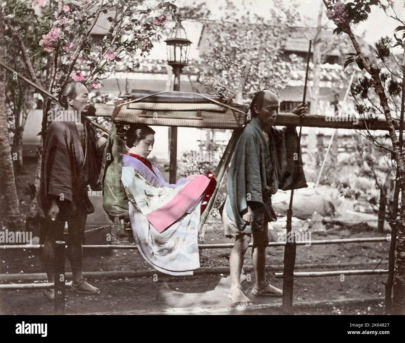 Vintage 19th century photograph - Japan - woman with porters in a kago or carrying chair. Stock Photo