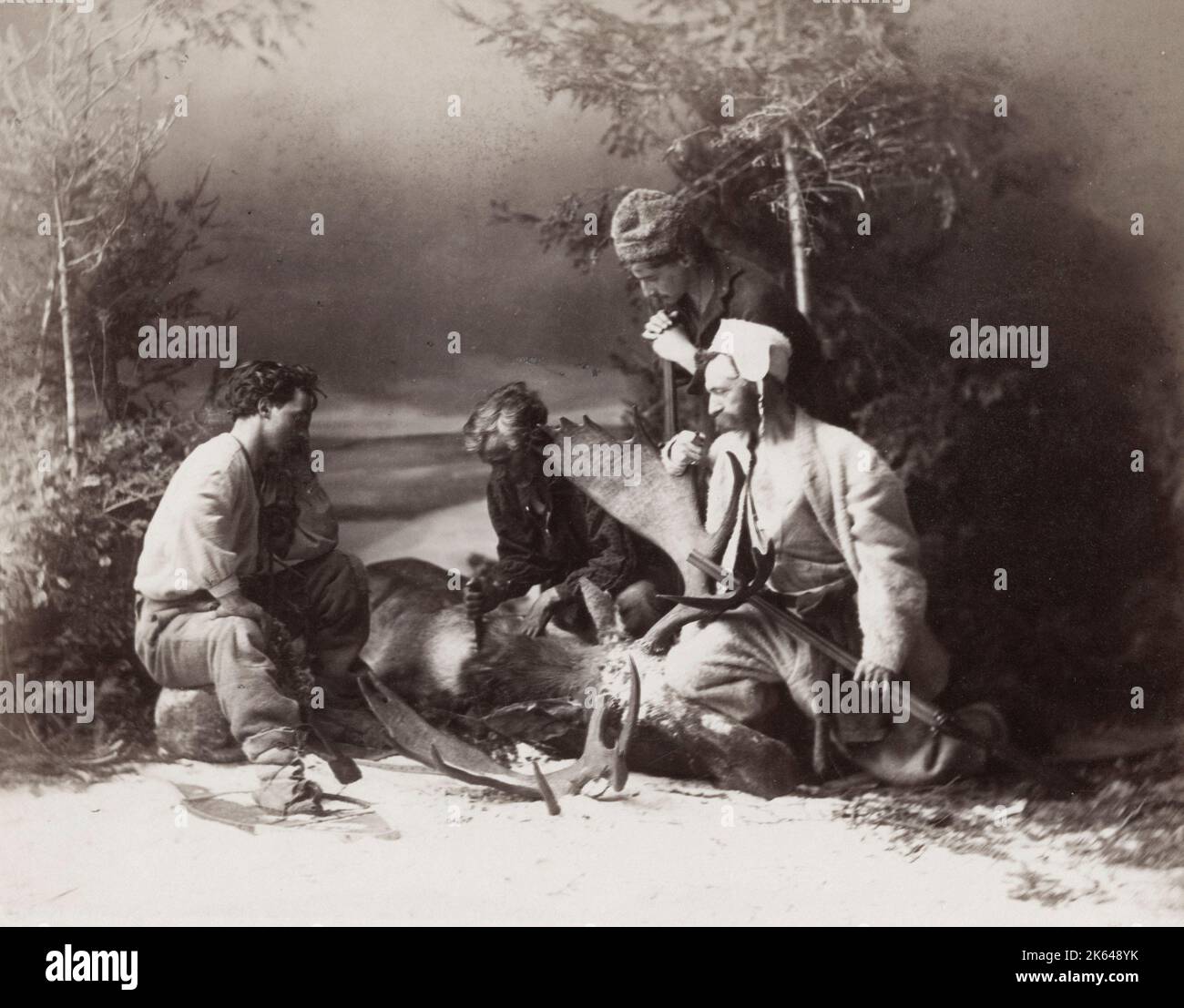 19th century vintage photograph - hunters skinning a deer in snow, studio composition by William Notman, Canada, c.1880s. Stock Photo