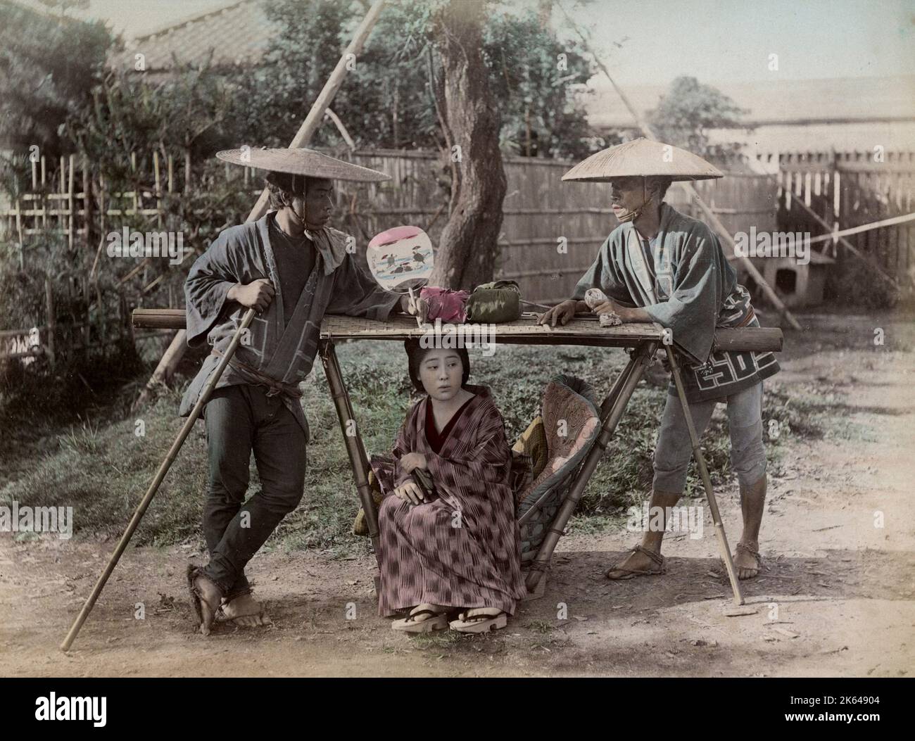 Late 19th century photograph: Young woman in carrying chair, kago, Japan, with porters. Stock Photo