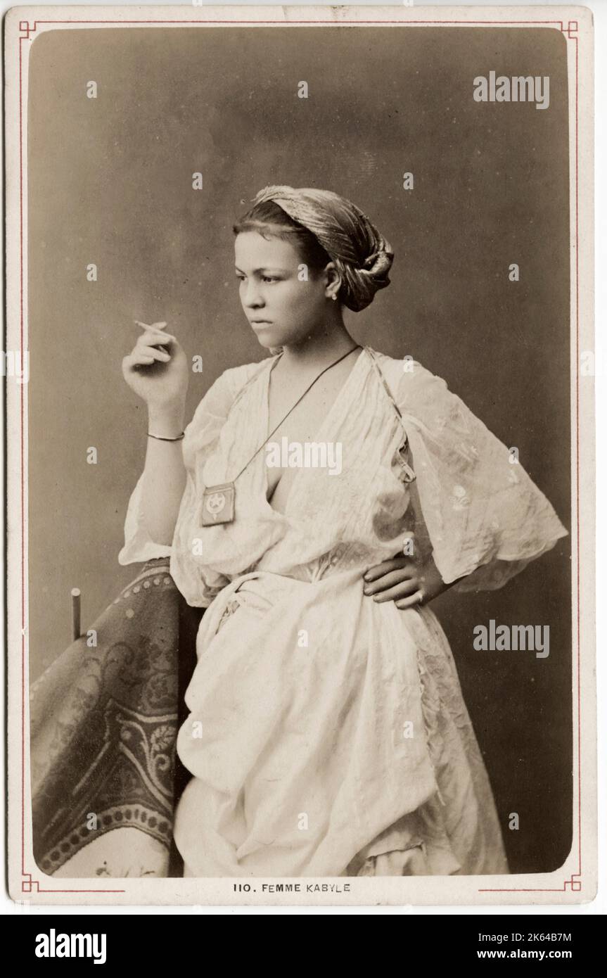 19th century vintage photograph - Kabyle woman with a cigarette. The Kabyle people are a Berber ethnic group indigenous to Kabylia in the north of Algeria, spread across the Atlas Mountains, one hundred miles east of Algiers. They represent the largest Berber-speaking population of Algeria and the second largest in North Africa. Stock Photo