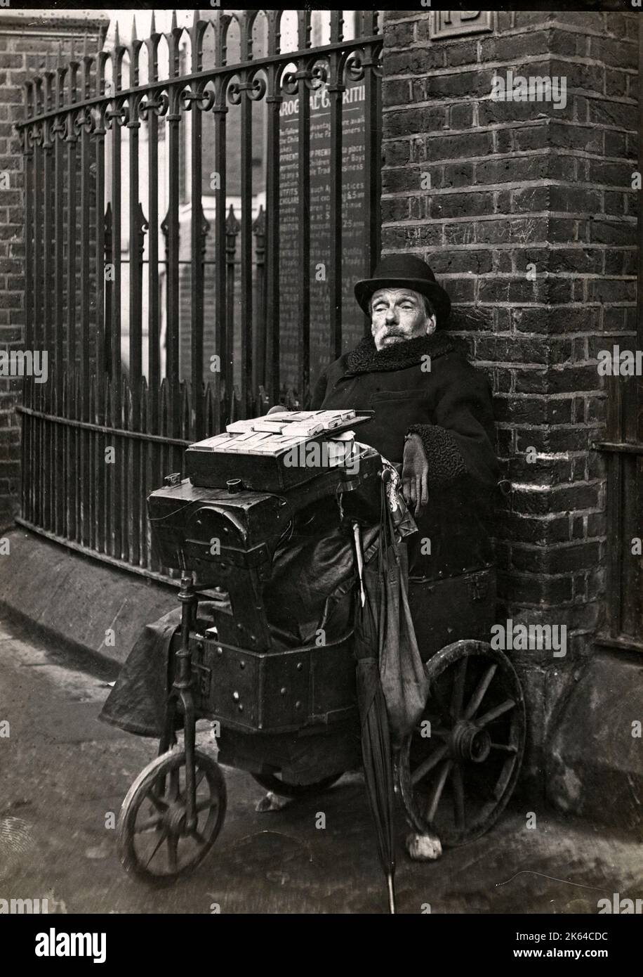 A disabled seller of matches and boot laces on a London street corner, c.1920s. Stock Photo