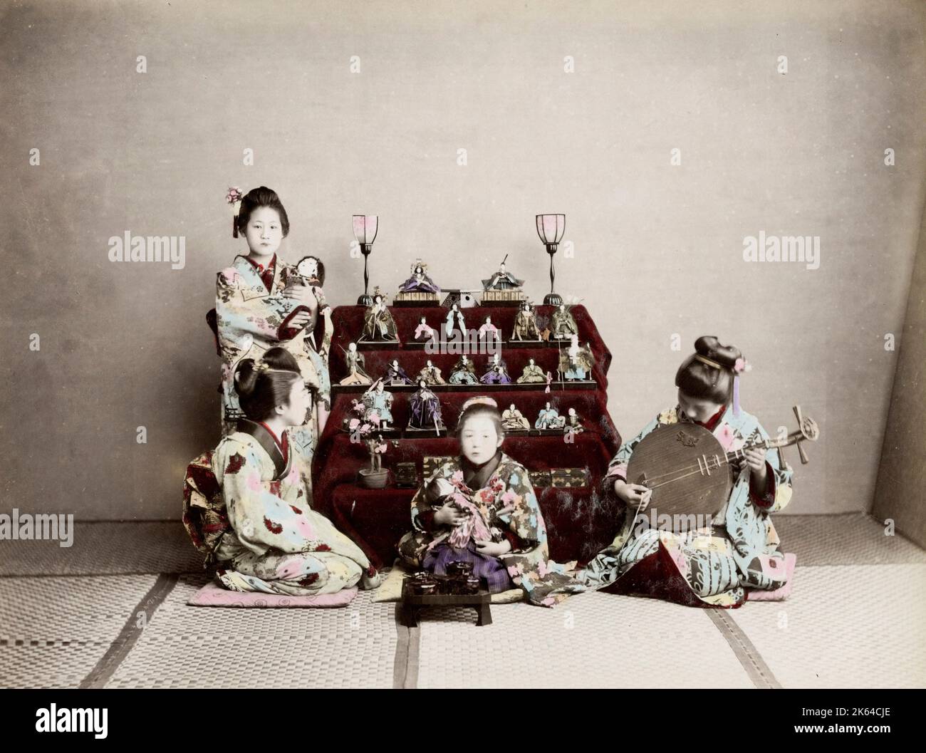 Vintage 19th century photograph - Meiji era Japan: Girls Festival, March. Hinamatsuri, also called Doll's Day or Girls' Day, is a special day in Japan. Celebrated on 3 March of each year, platforms covered with a red carpet-material are used to display a set of ornamental dolls representing the Emperor, Empress, attendants, and musicians in traditional court dress of the Heian period. Stock Photo