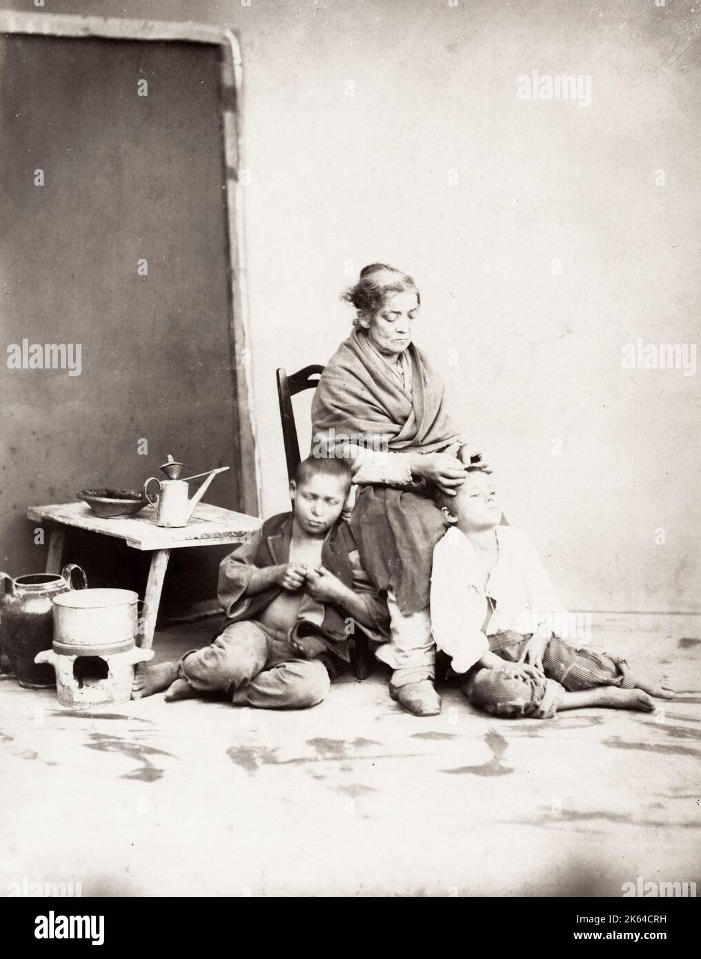 19th century vintage photograph: genre image by Giorio Sommer of an old women picking nits from the heads of two young children. Social history, poverty, Italy, Stock Photo