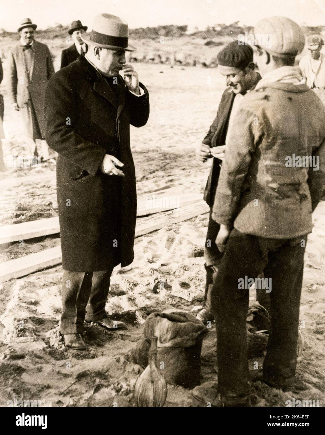 Early 20th century vintage press photograph - Italian fascist leader Benito Mussolini eating mussels while visting fishermen in Ostia, Rome, c.1920s Stock Photo