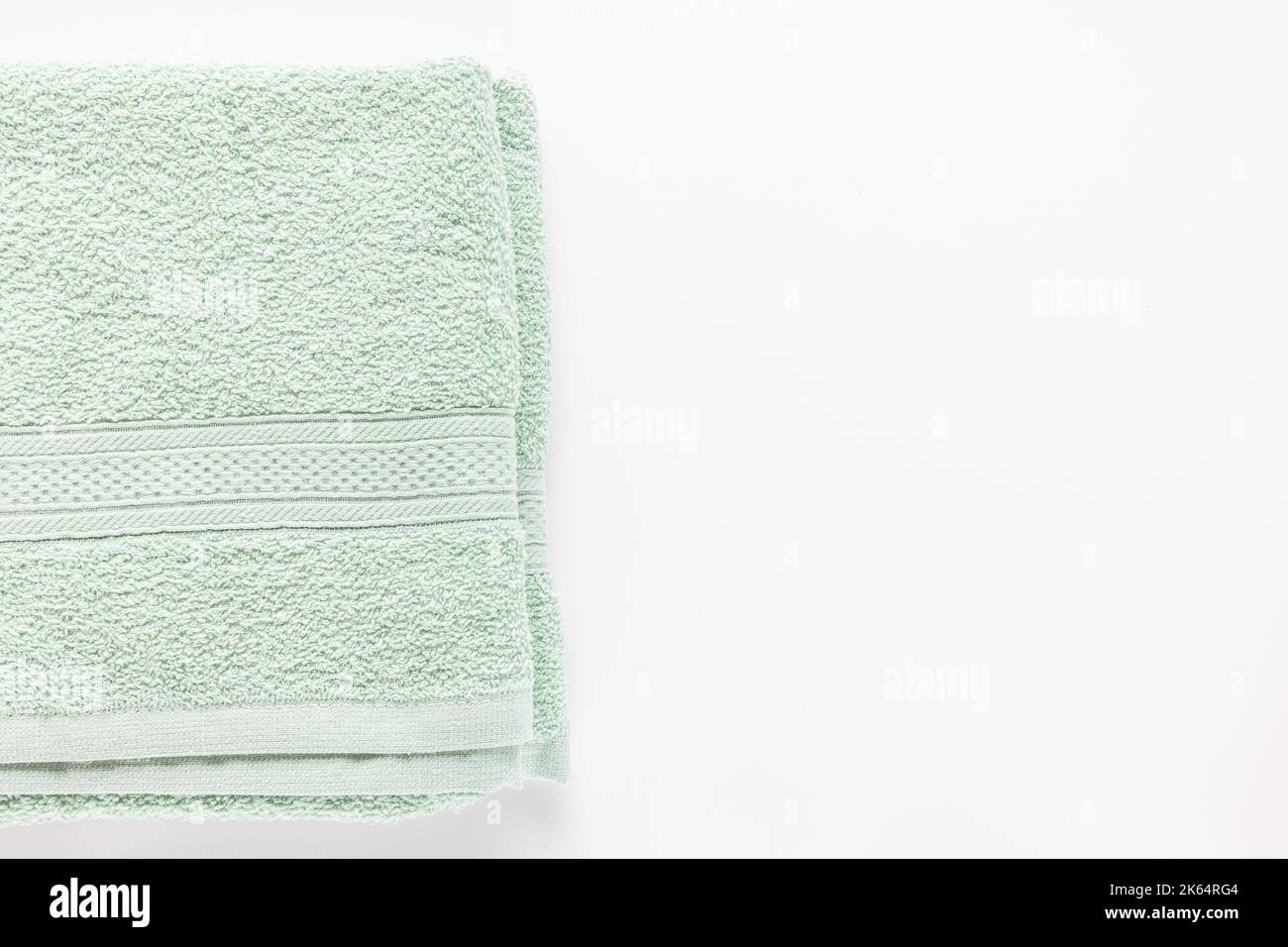 New folded mint green bath sheet or towels on white background. Top view, copy space Stock Photo