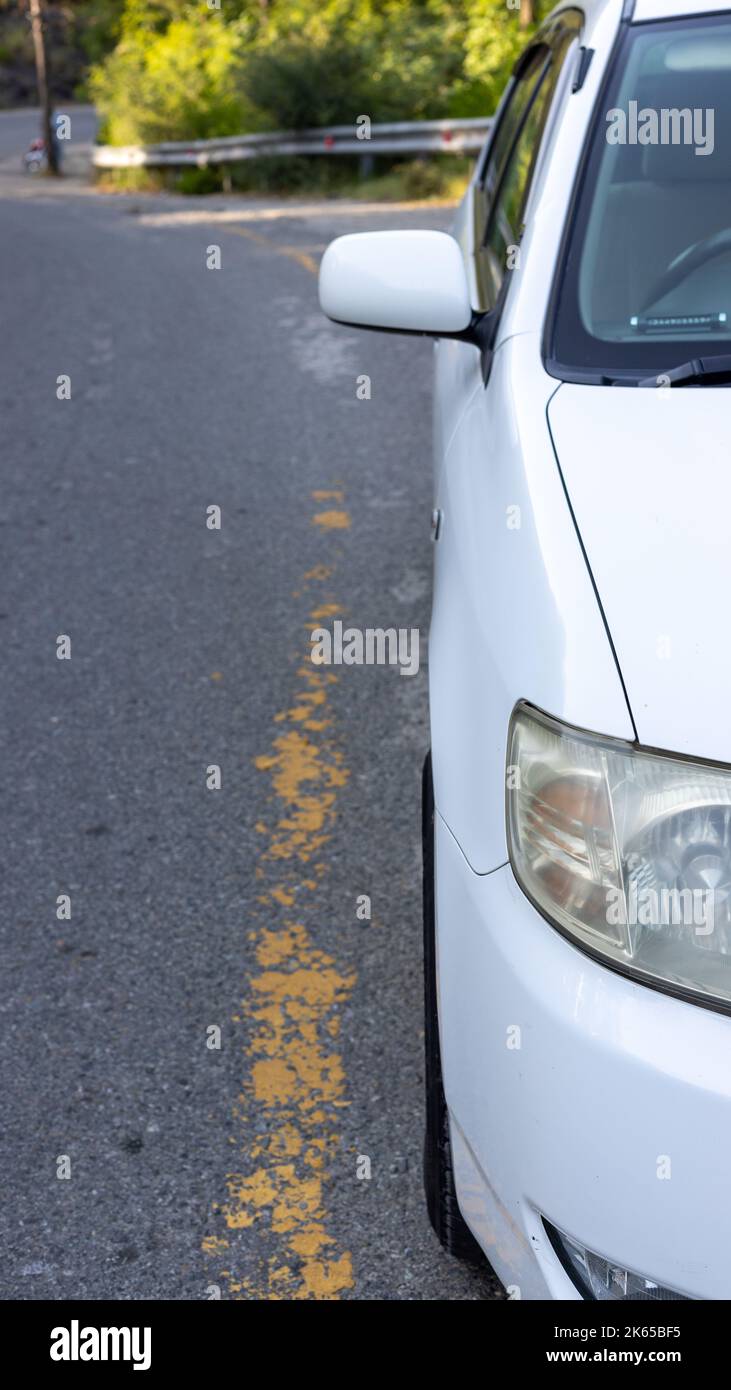 A white car parked on the side of an asphalt road Stock Photo